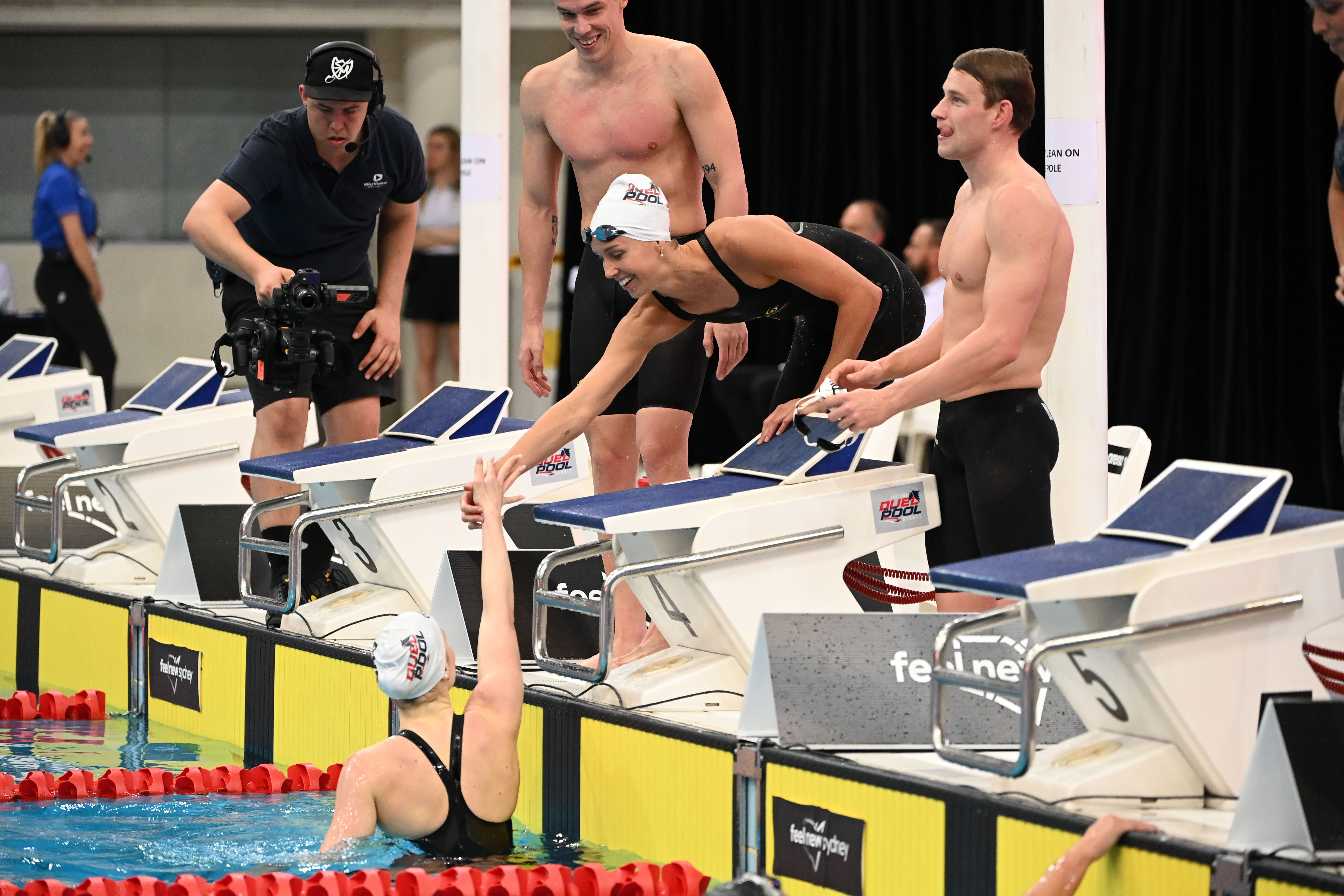 Emma McKeon leans over the congratulate Mollie O'Callaghan after the Australians took out the mixed 4x100m freestyle relay. Image: Delly Carr / Swimming Australia