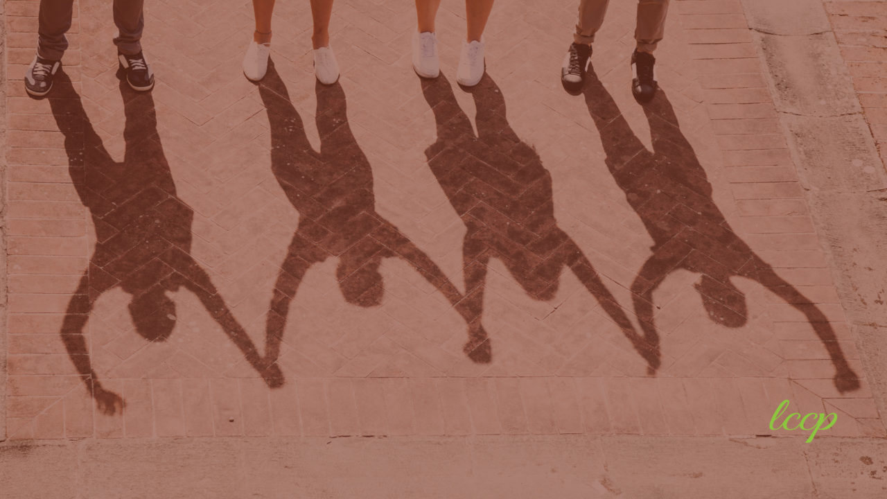 Shadow of people holding hands that are raised in the air. 