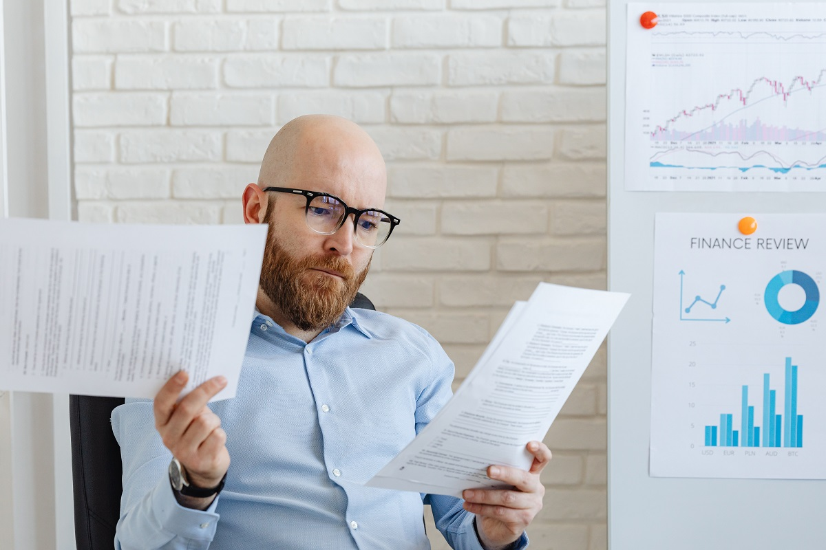 bald guy wearing glasses in his office looking at paperwork