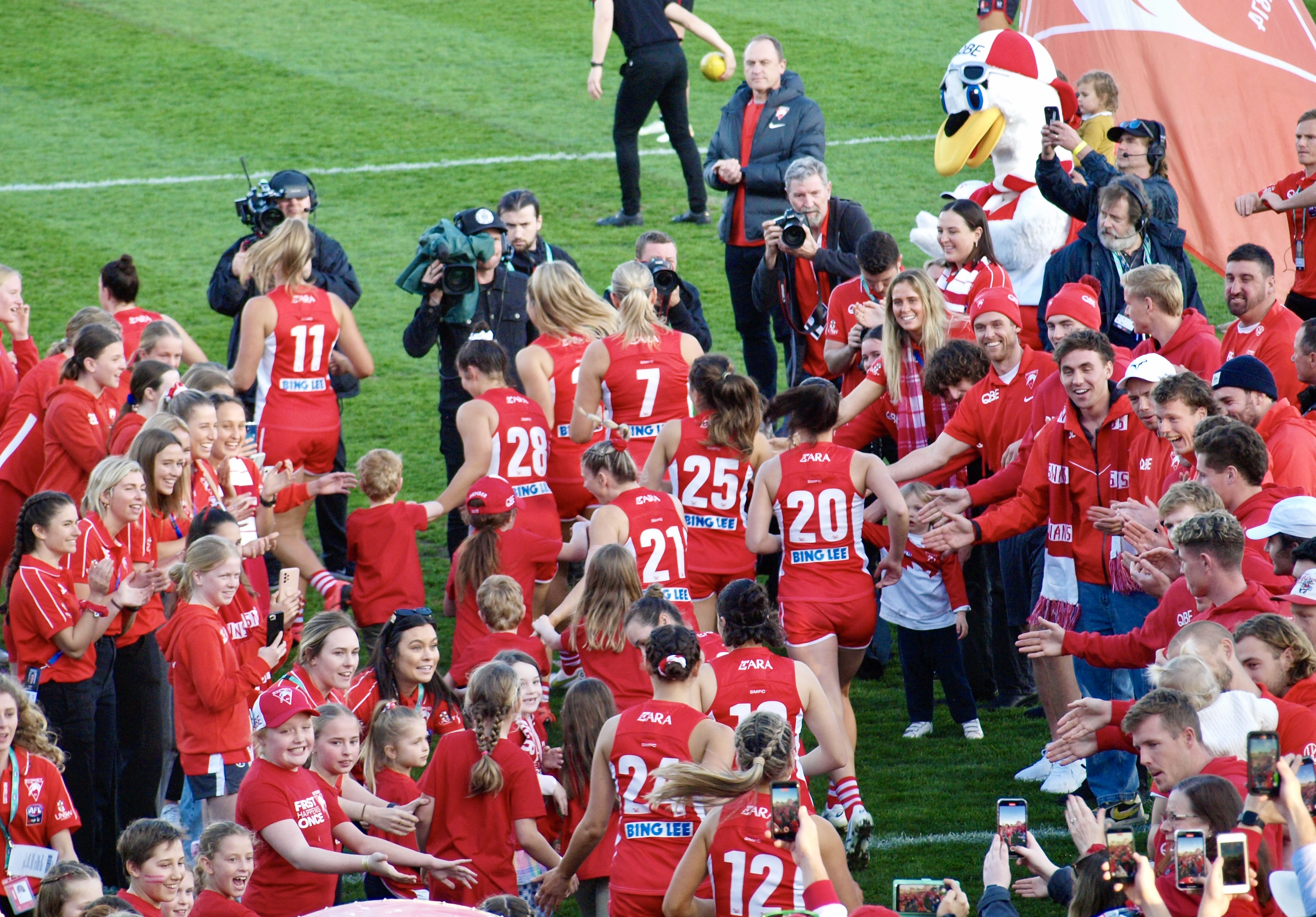 The Sydney Swans AFLW team runs through the guard of honour and out onto the field.