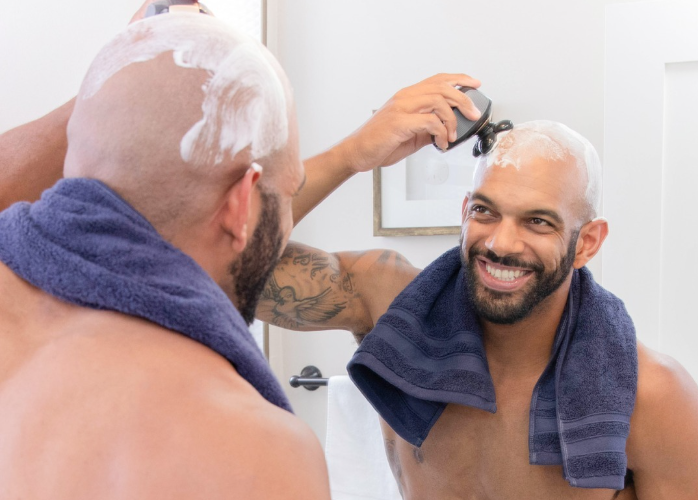 Man shaving his head in the mirror