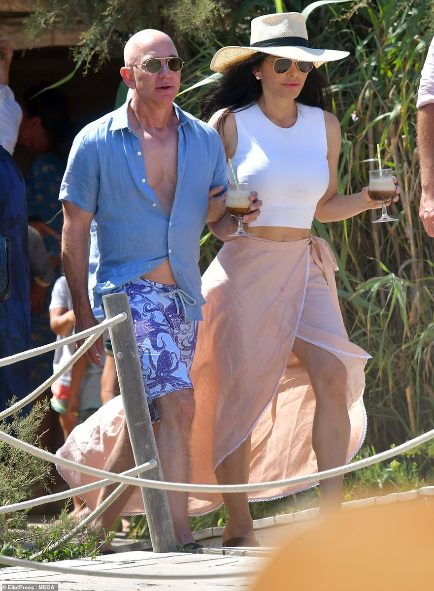 Jeff Bezos wearing sunglasses with Lauren Sanchez by his side