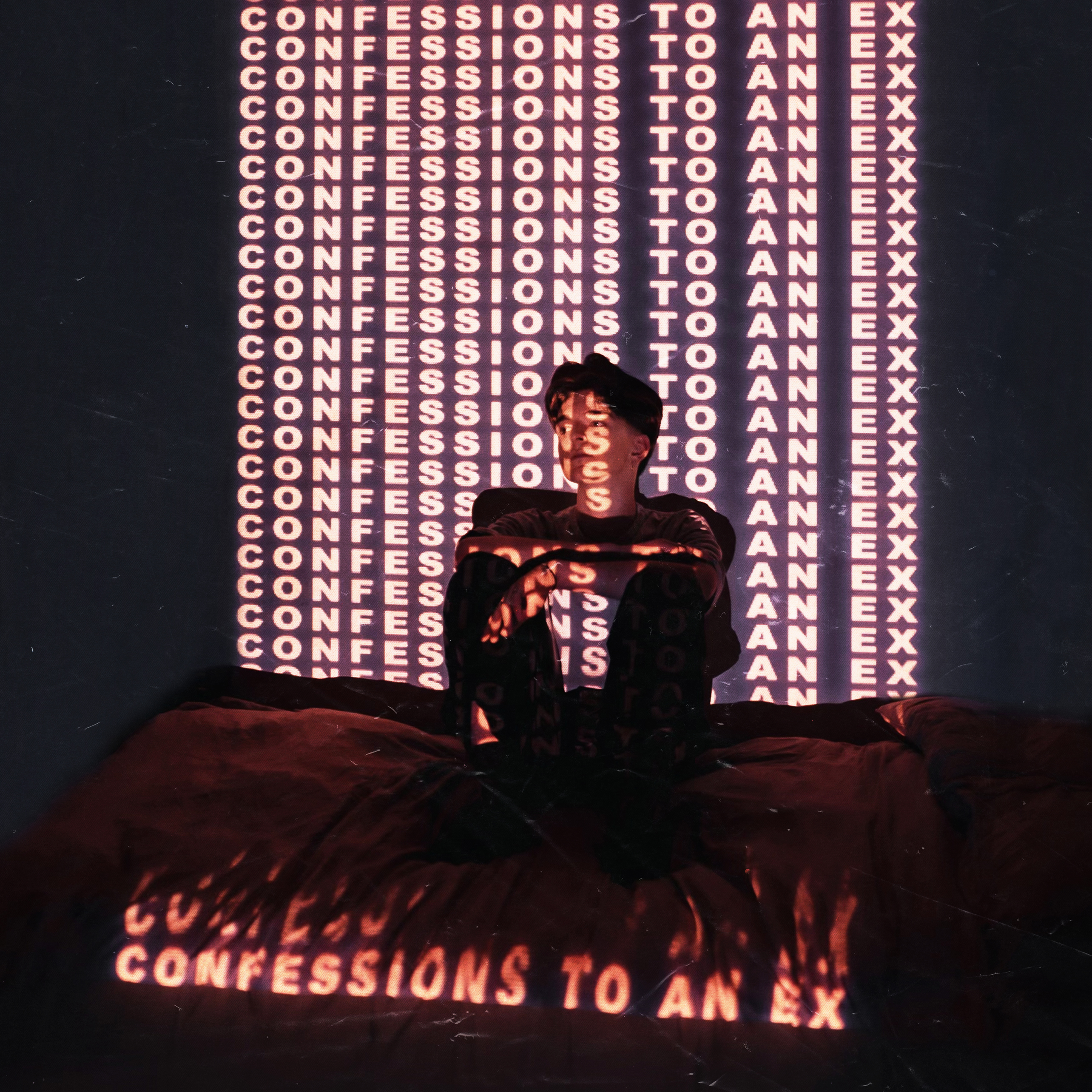 Daphnie sitting on the floor with 'Confessions to an Ex" in flames in front of him and also projected multiple times onto the wall behind him [PHOTO: Supplied]