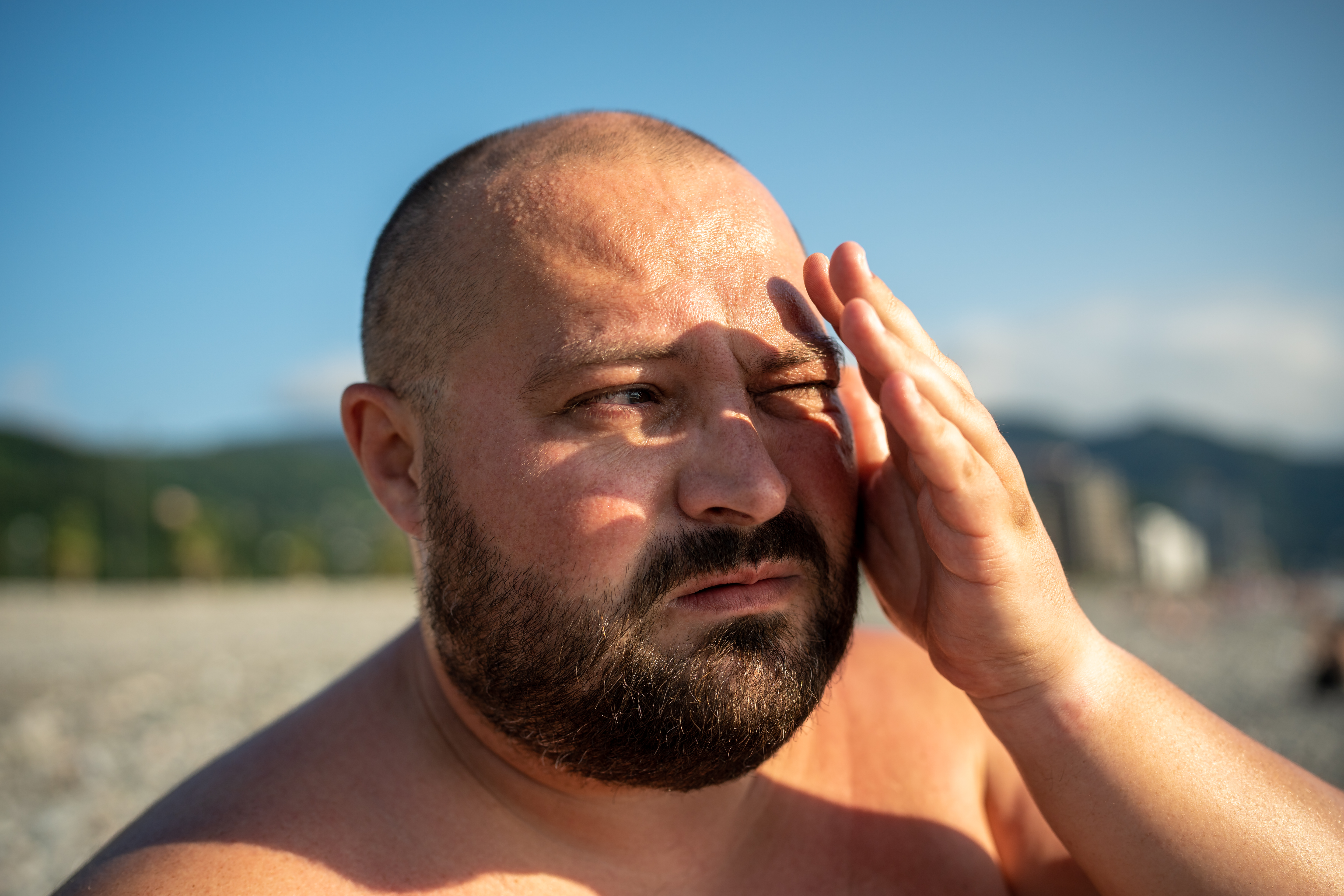 bald man shielding eyes from sun