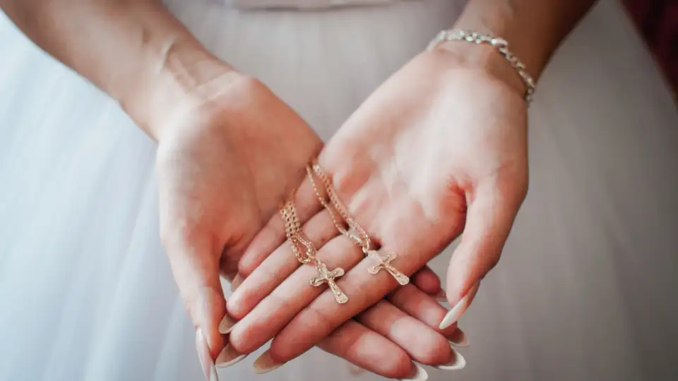 Bide holding yellow gold cross necklaces from Glor-e.