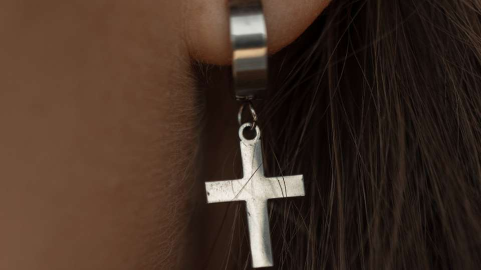 Side view of a woman wearing a pair of cross earrings