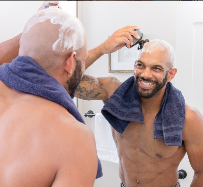 Man shaving his head in the bathroom mirror