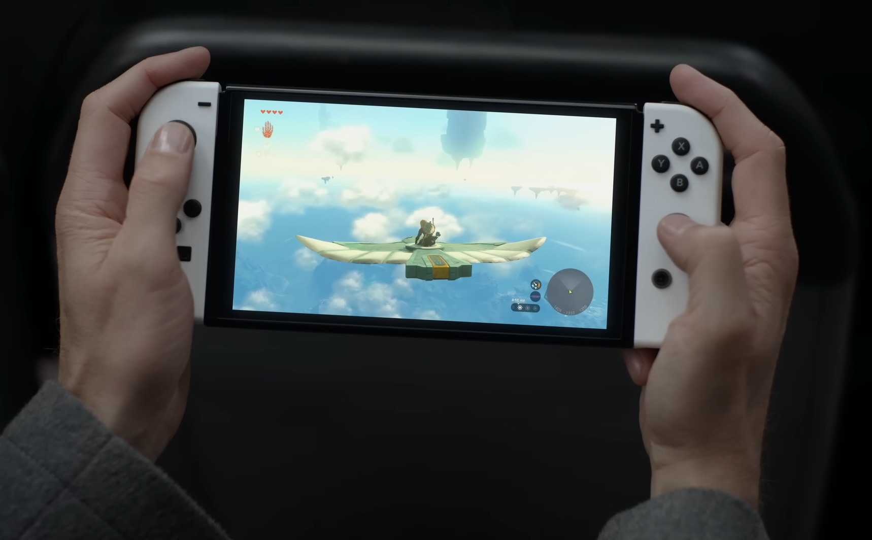 The man plays his Switch on the bus. In-game, Link is gliding atop a Zonai flying device