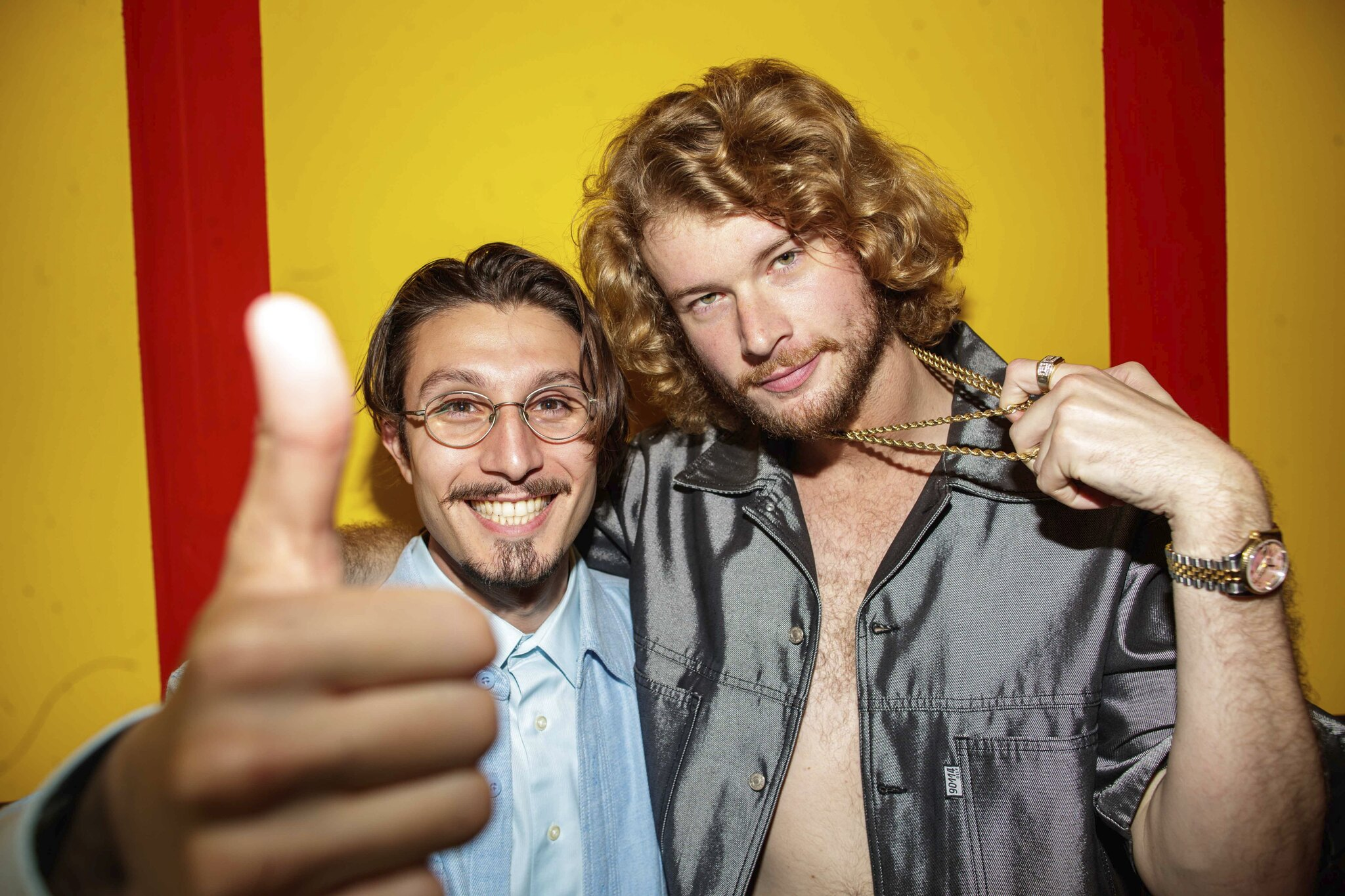 bbno$ (left0 with Yung Gravy (right) in front on a striped yellow and red wall