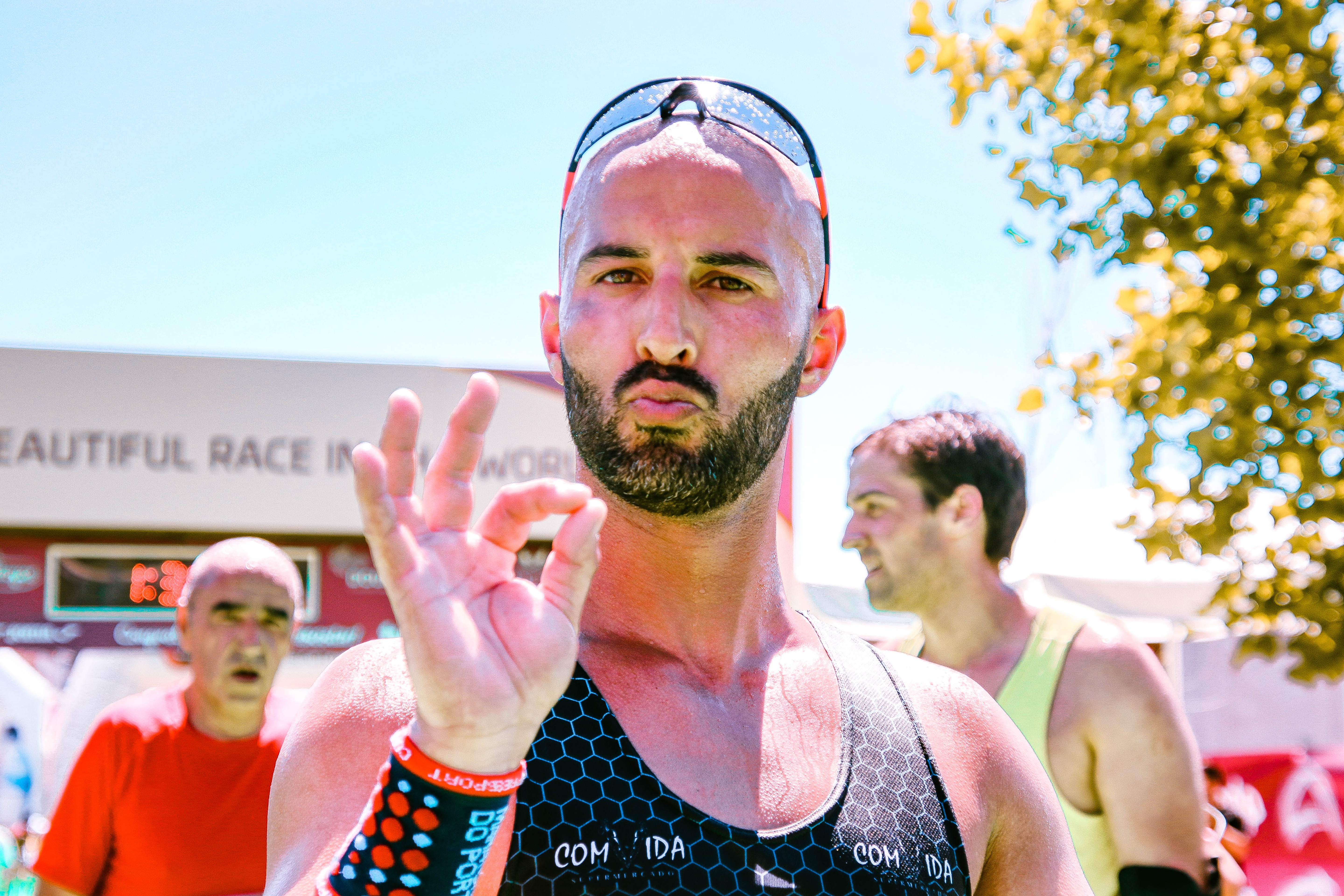 bald marathon runner wearing sunglasses doing the ok hand sign 