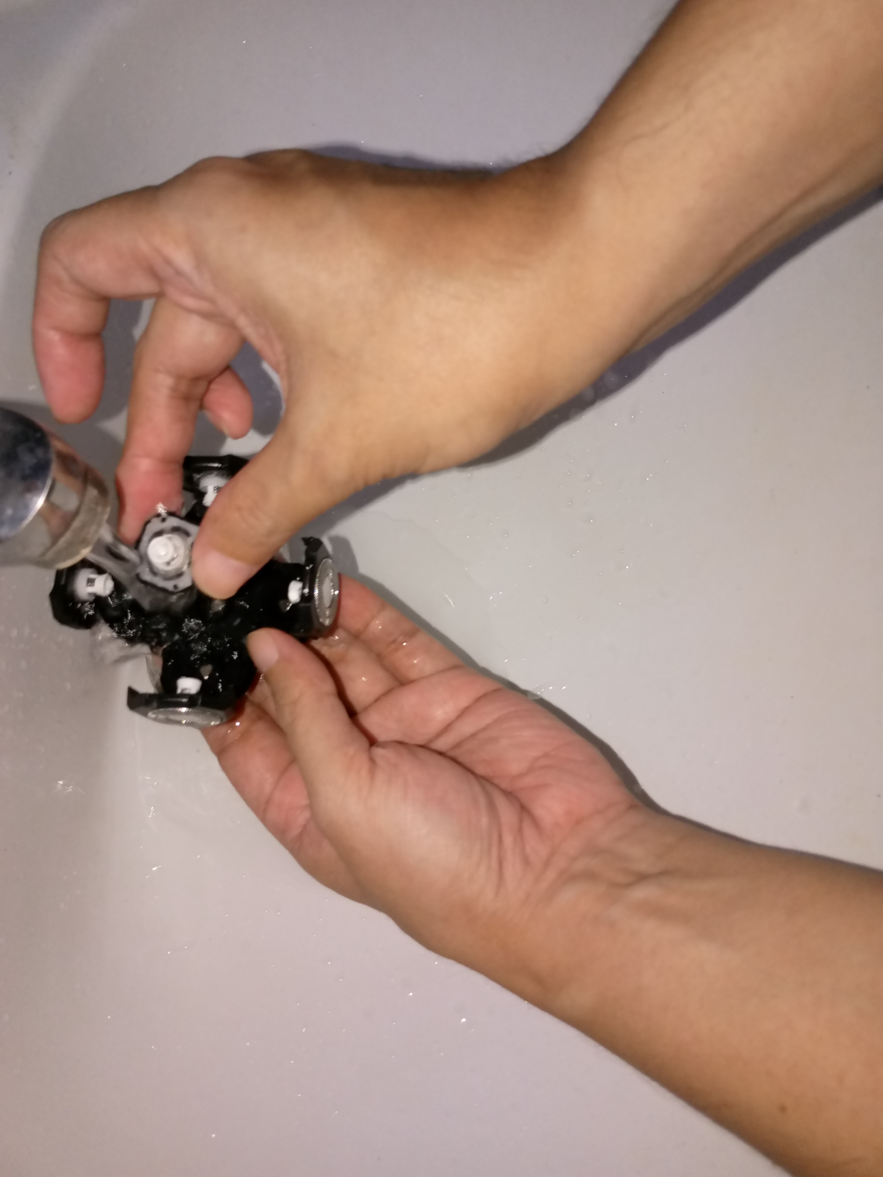 5 head rotary shaver blades being rinsed in running water