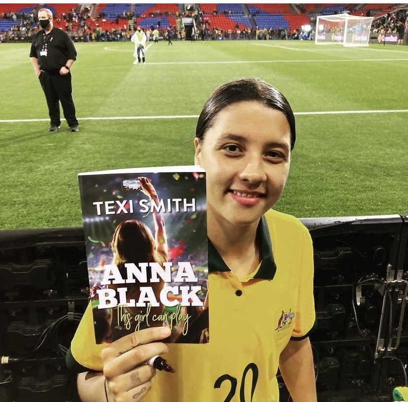 Sam Kerr poses with a copy of Anna Black after a Matildas game
