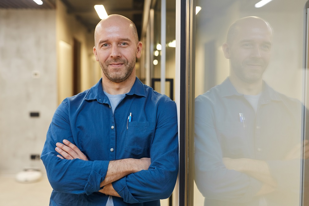 bald man smiling confidently with arms crossed 