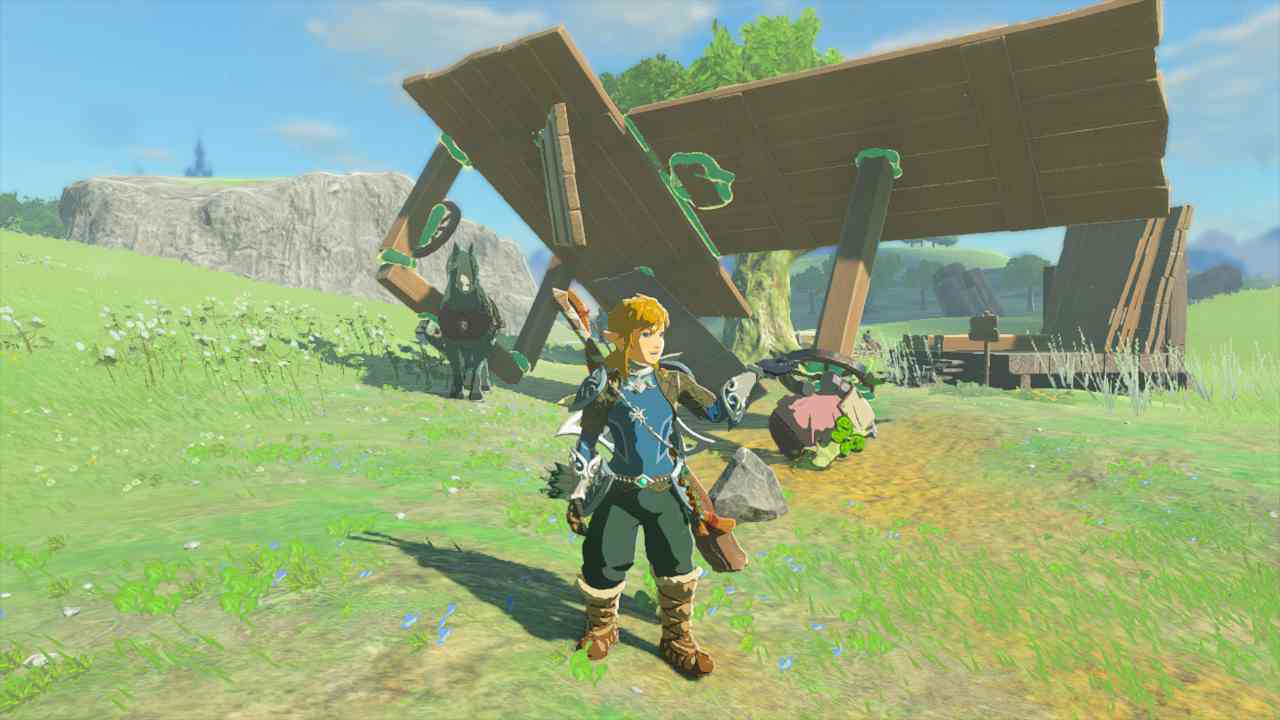 Link posing in front of a capsized failed construction of random wooden parts.