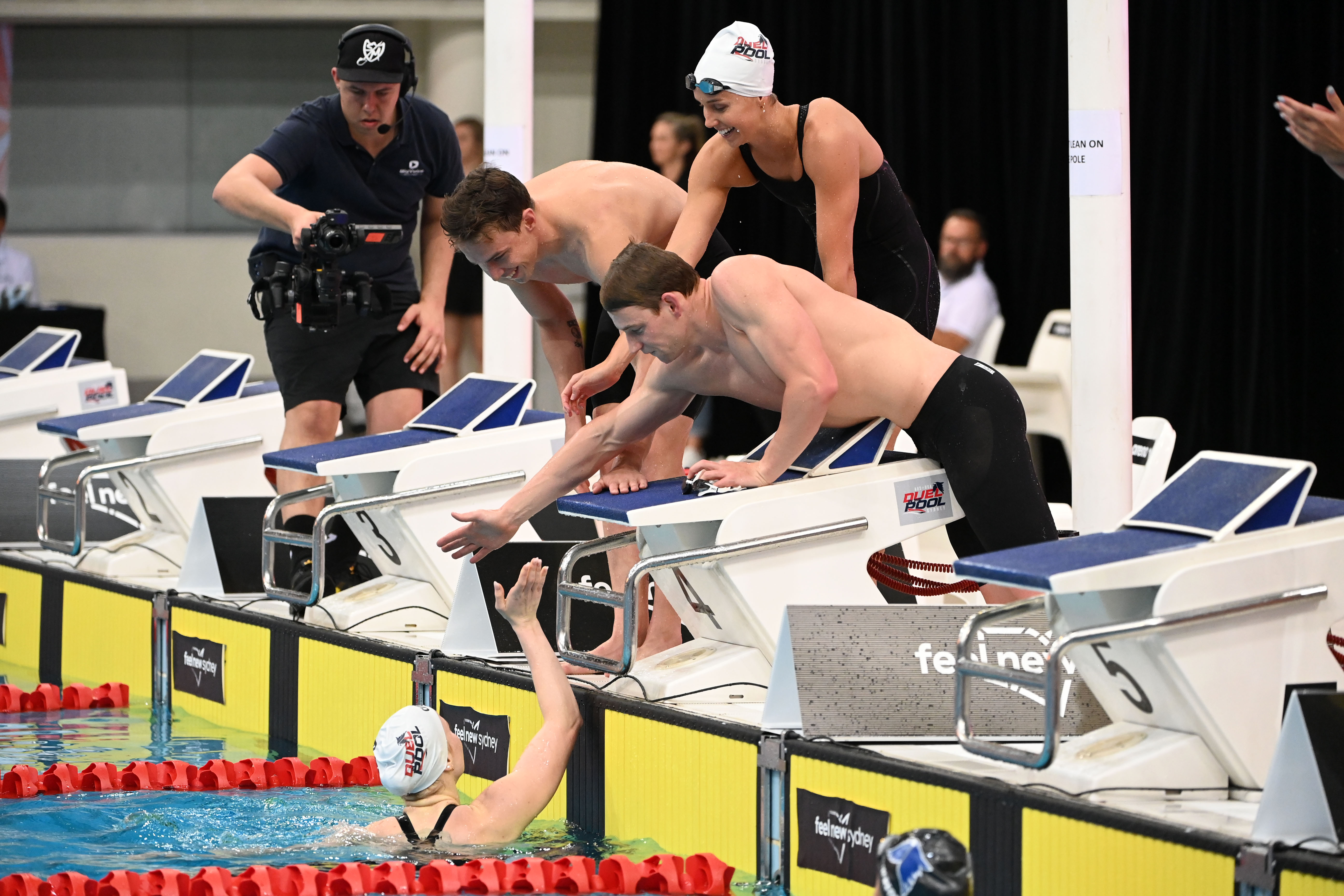 Mollie O'Callaghan (in the water) is congratulated by teammates after winning a relay for Australia at Duel in the Pool. Image: Delly Carr / Swimming Australia