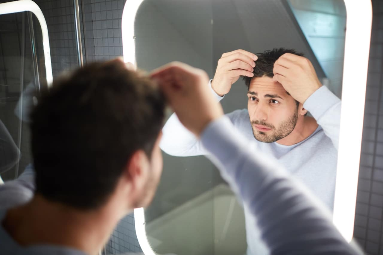 Guy checking his hair in the mirror