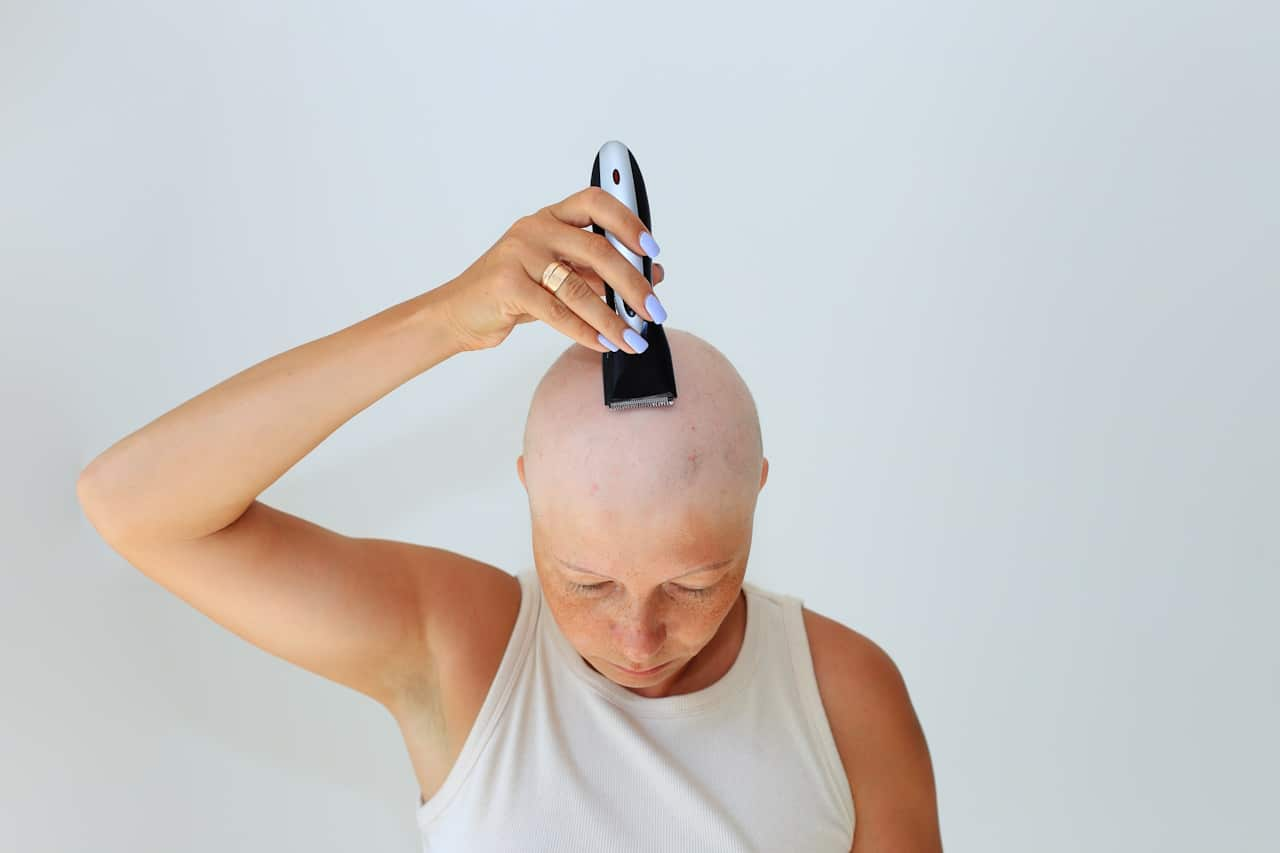 A woman shaving her head due to hair loss