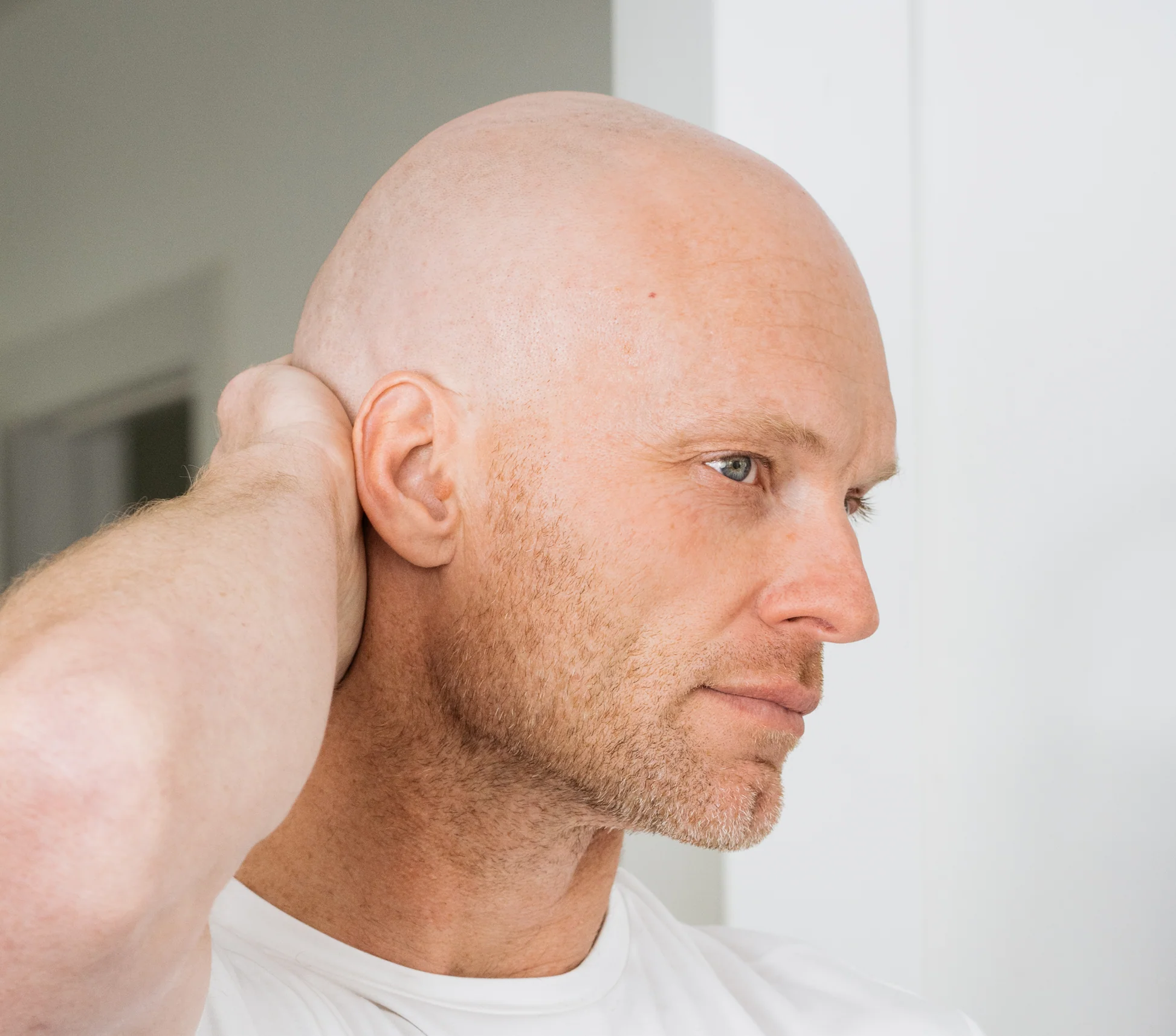 bald man applying moisturizer